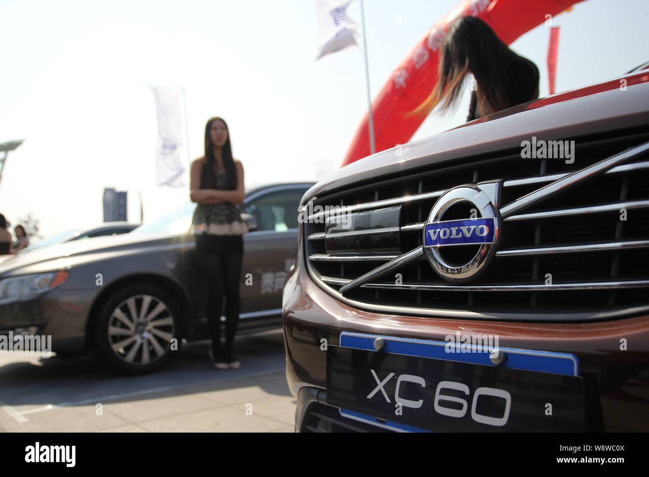 --FILE--Models pose with Volvo cars at an auto show in Qingdao city, east Chinas Shandong province, 15 March 2014.    The Chinese billionaire owner of Stock Photo