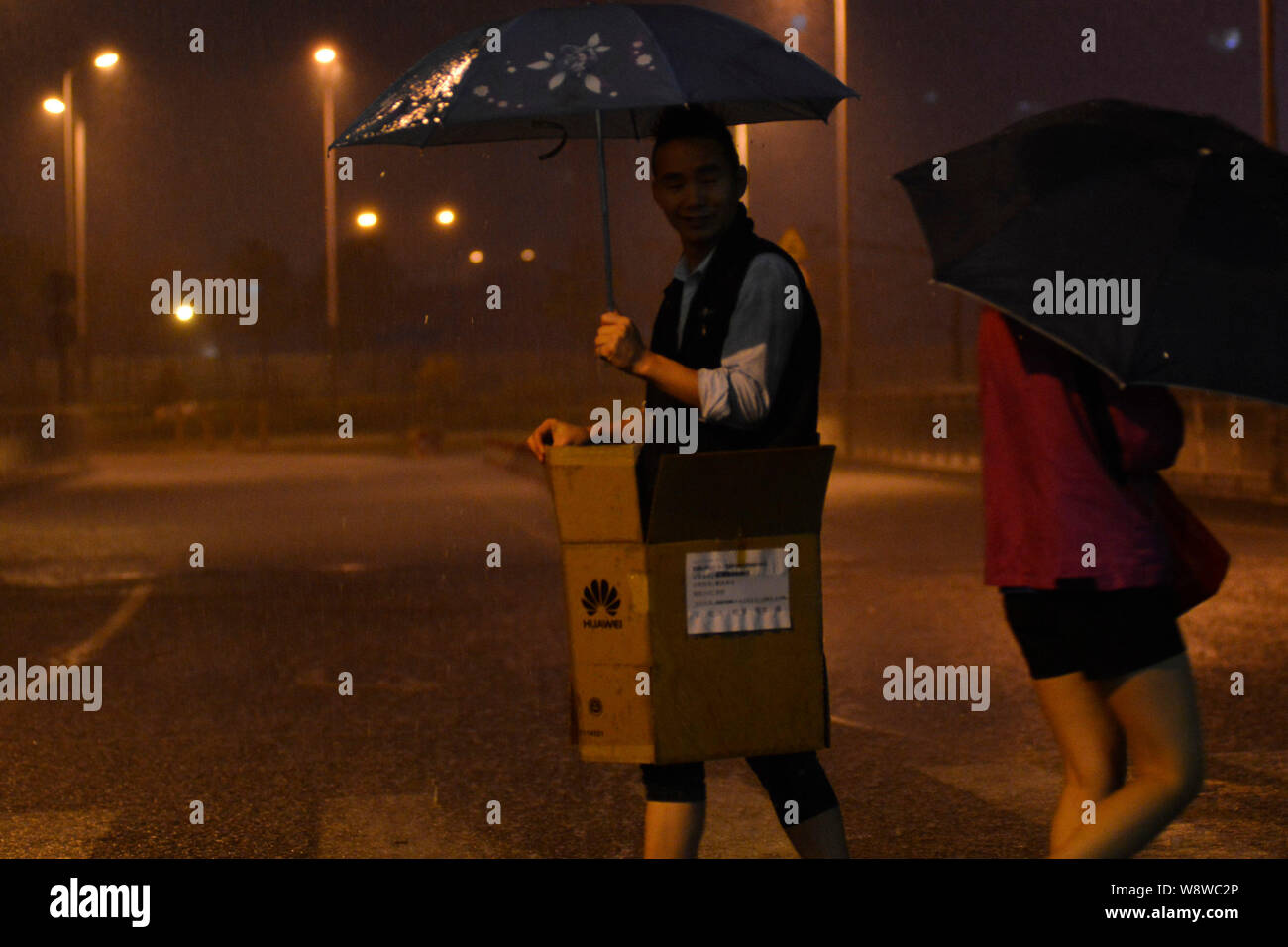 Pedestrians walk across a road in heavy rain in Shenzhen city, south Chinas Guangdong province, 30 March 2014.   Heavy rains have grounded flights and Stock Photo