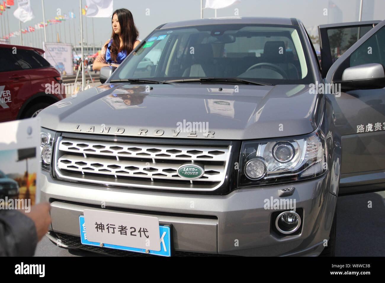 --FILE--A model poses with a Land Rover Freelander 2 during an automobile exhibition in Qingdao city, east Chinas Shandong province, 15 March 2014. Stock Photo