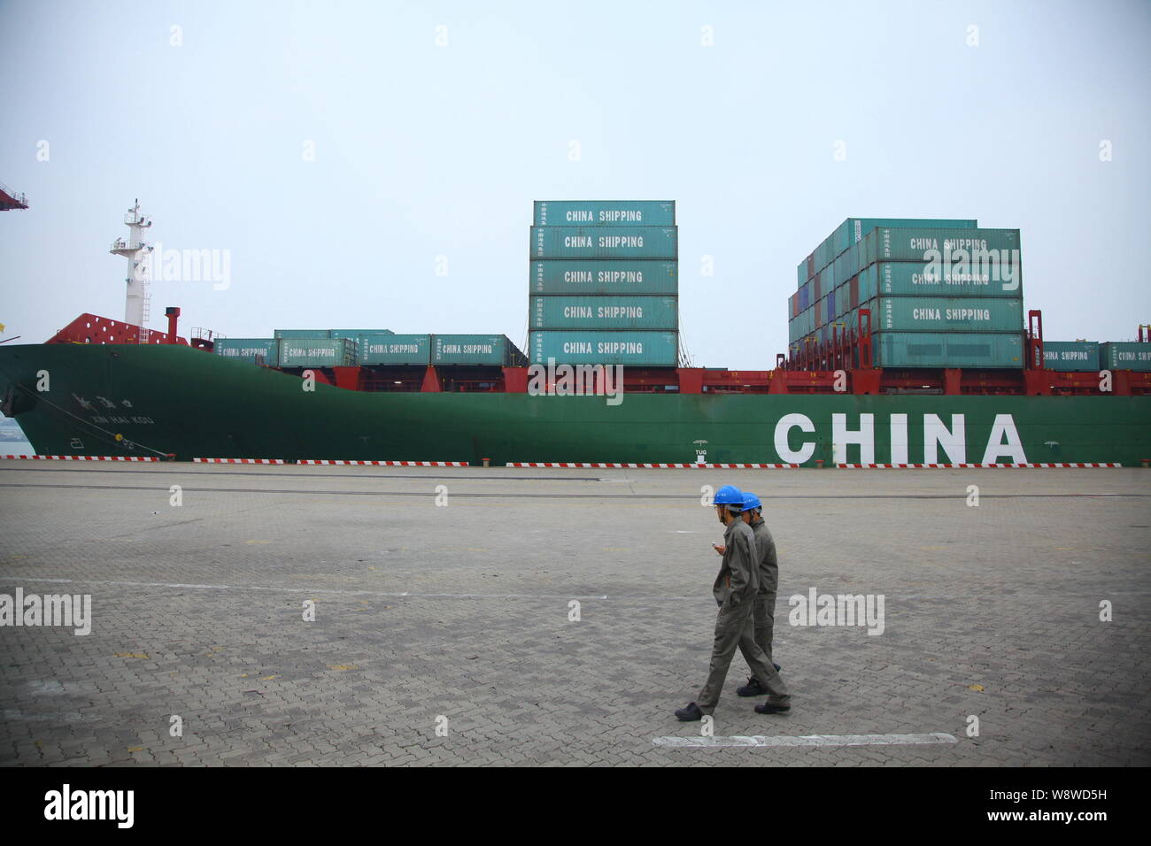 --FILE--Chinese workers walk past a container ship loaded with ...