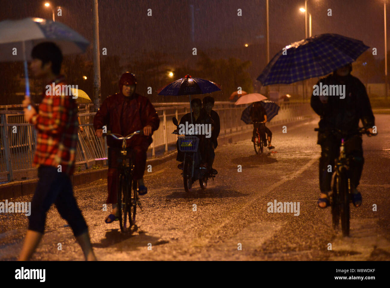 Cyclists ride in heavy rain on a road in Shenzhen city, south Chinas Guangdong province, 30 March 2014.   Heavy rains have grounded flights and strand Stock Photo