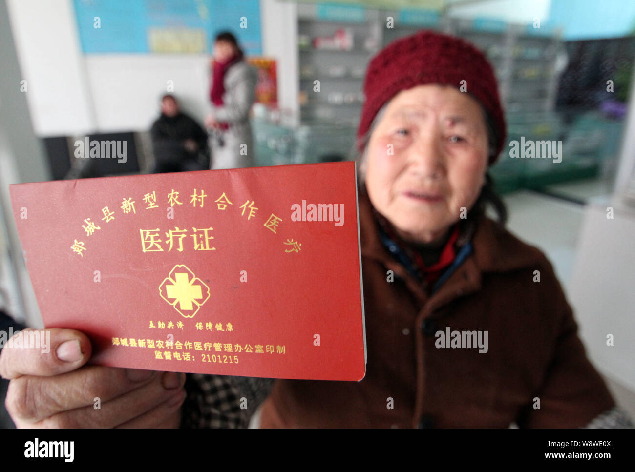 An elderly local Chinese resident shows her health insurance card at a health station in Tianzhan village, Matou Town, Tancheng county, Linyi city, ea Stock Photo