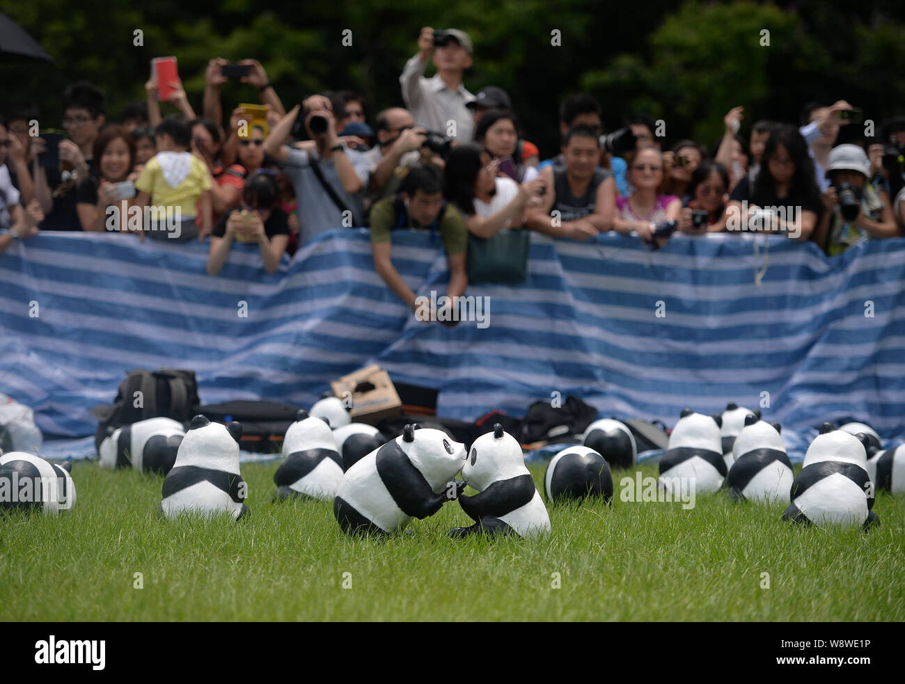 Visitors take photos of the paper pandas created by French artist Paulo Grangeon on display at Victoria Park during the 1600 Pandas World Tour in Hong Stock Photo