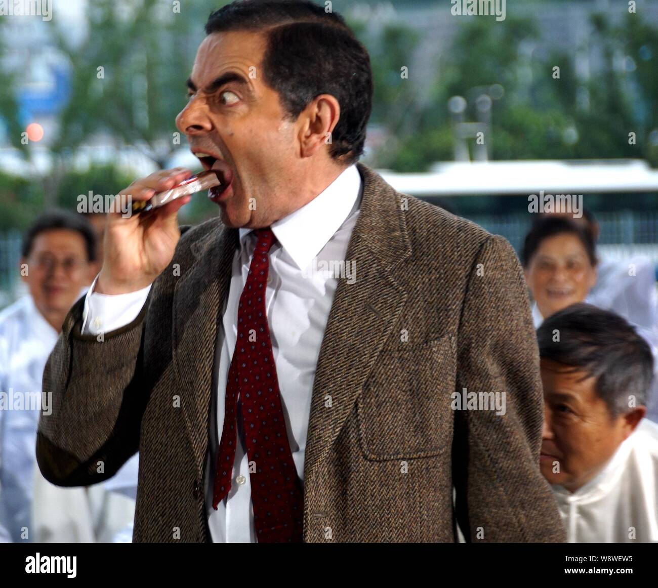 English actor Rowan Atkinson eats a bar of chocolate as he plays Mr. Bean during a filming session for a TV commercial at the Mercedes-Benz Arena in S Stock Photo