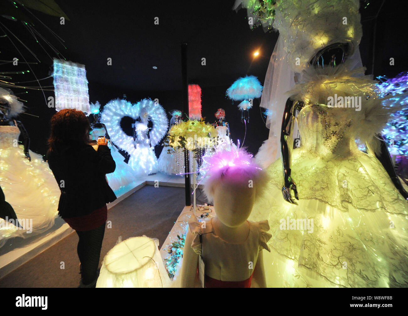 A visitor walks past illuminated fibre optic wedding dresses on display at the China Wedding Expo 2014 in Shanghai, China, 24 February 2014.   The Chi Stock Photo