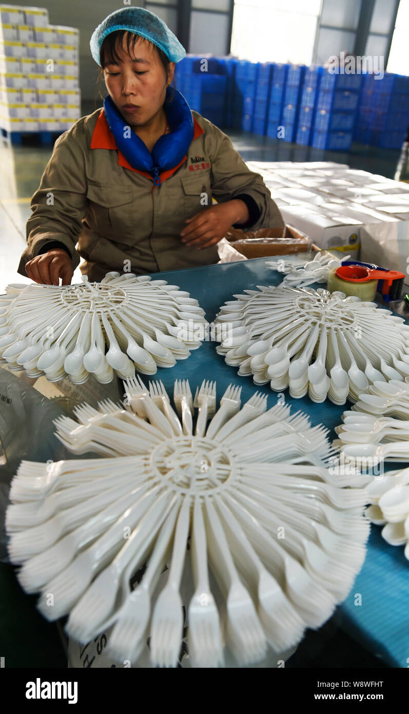 --FILE--A female Chinese worker checks degradable disposable spoons and forks to be exported to Southeast Asia at a factory in Handian town, Zouping c Stock Photo