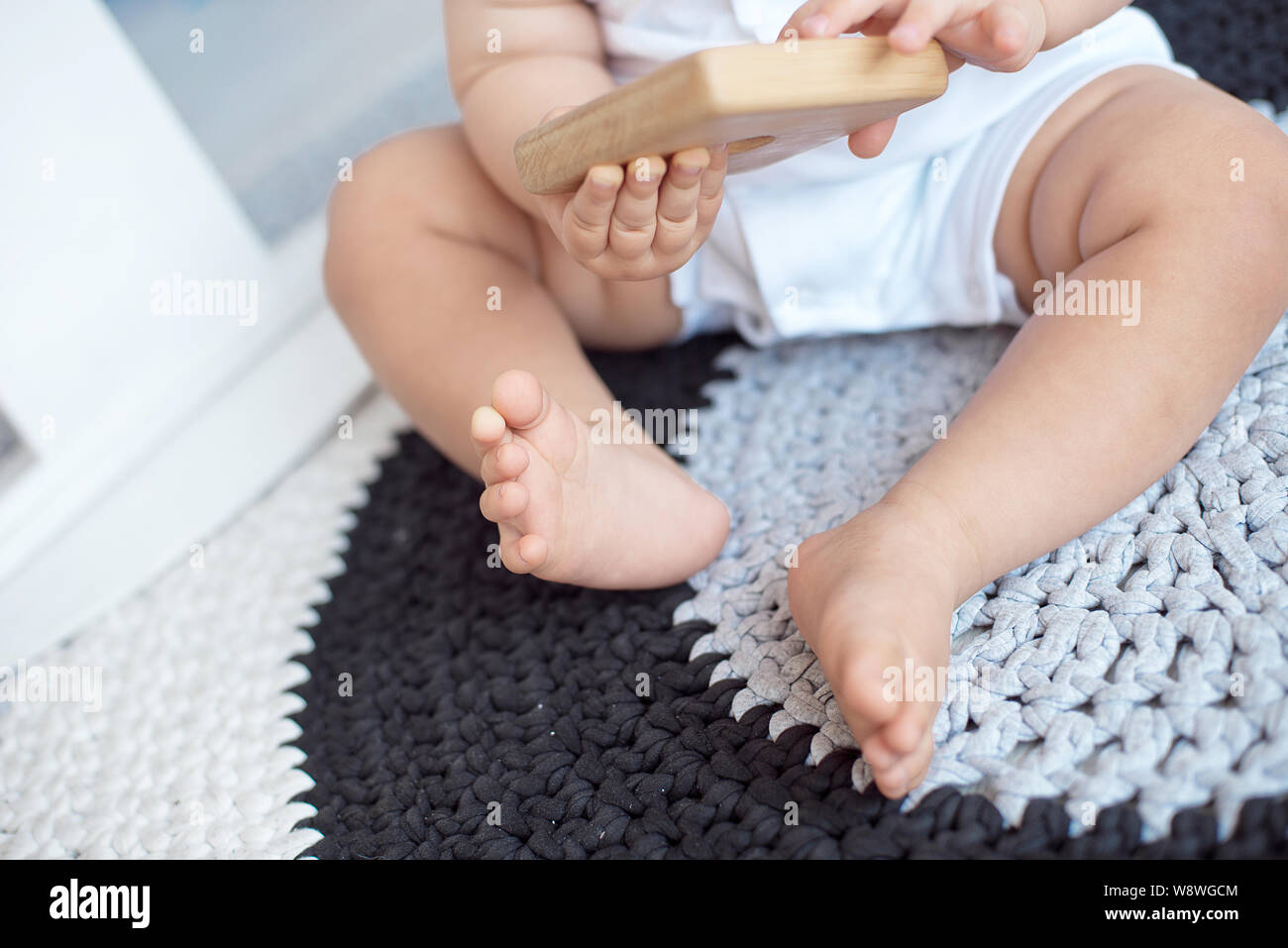 Cute baby in blue overalls sits on a knitted carpet Stock Photo Alamy