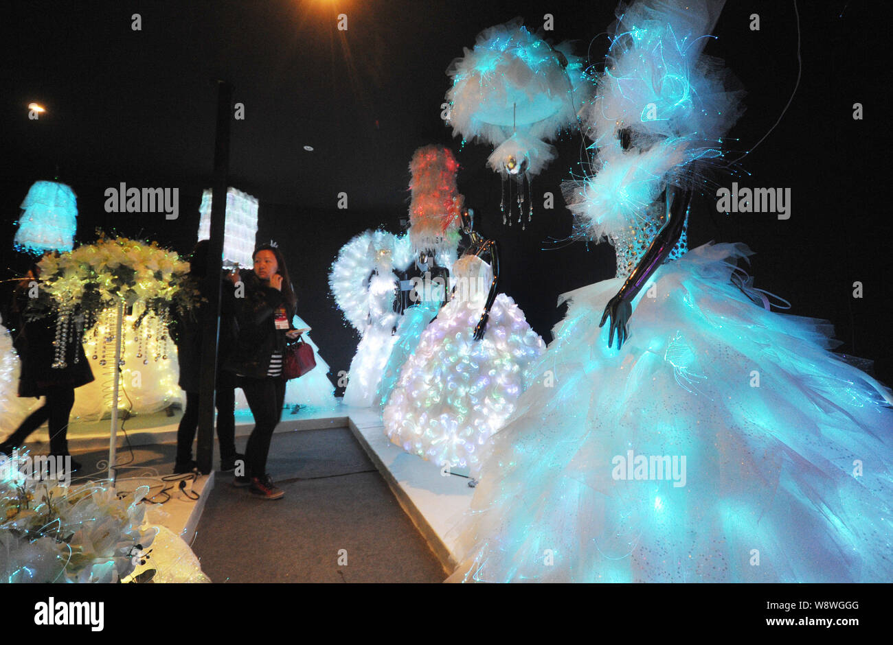 Visitors look at illuminated fibre optic wedding dresses on display at the China Wedding Expo 2014 in Shanghai, China, 24 February 2014.   The China W Stock Photo