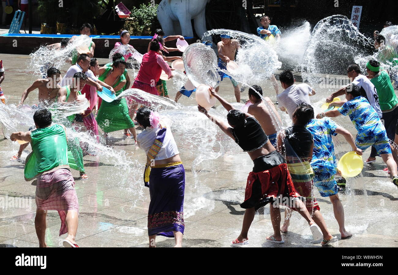 Chinese tourists and entertainers splash water during the water