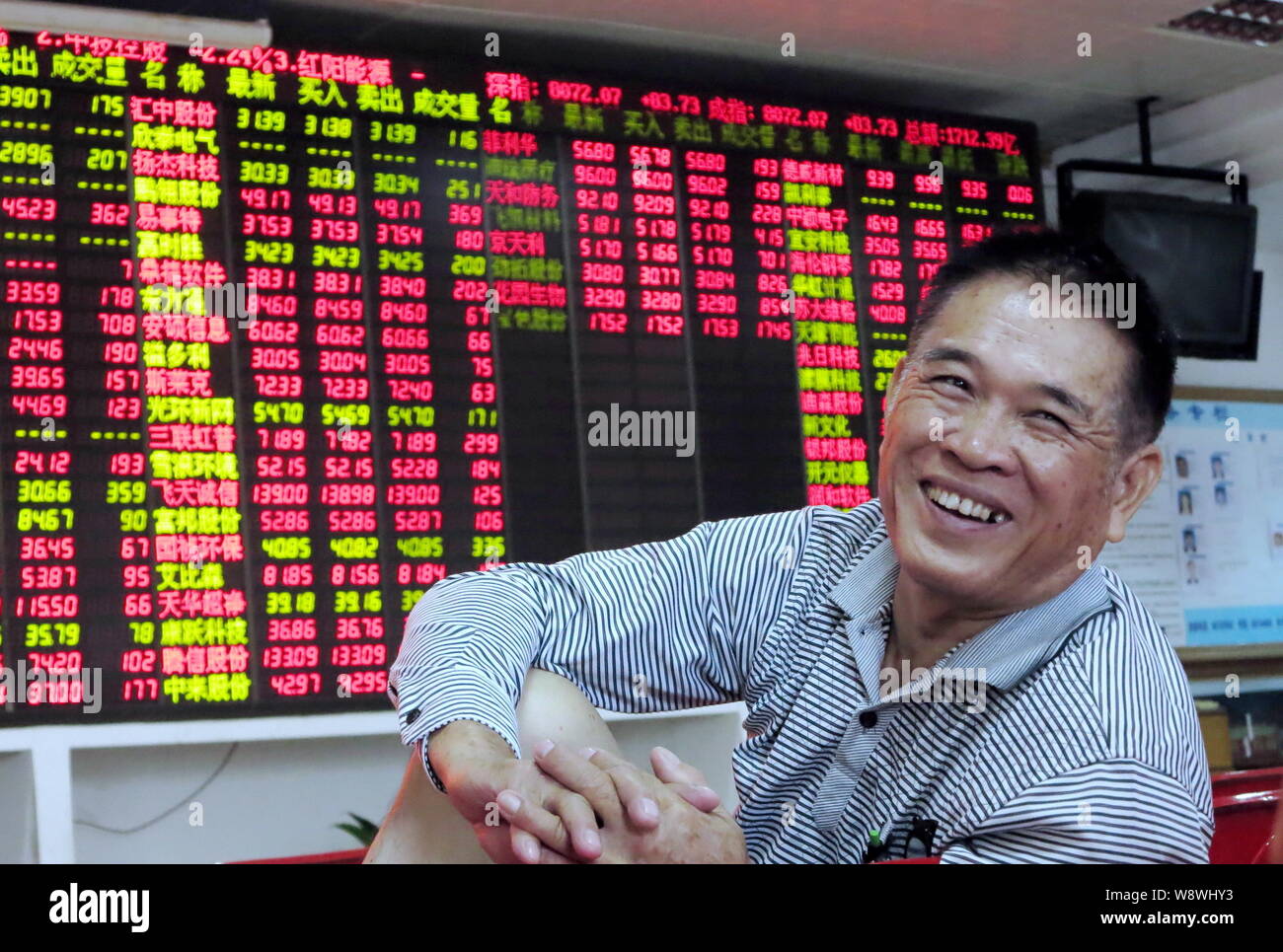 A Chinese investor smiles while talking with others as they view prices of  shares (red for price rising and green for price falling) at a stock broker  Stock Photo - Alamy