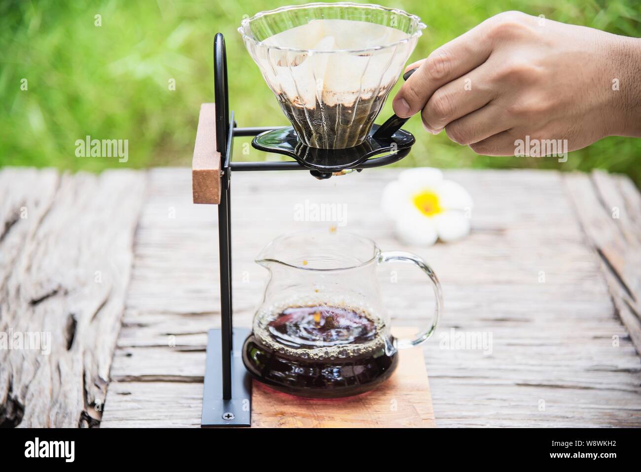 Man making drip fresh coffee in vintage coffee shop with green nature background - people with fresh coffee in nature concept Stock Photo
