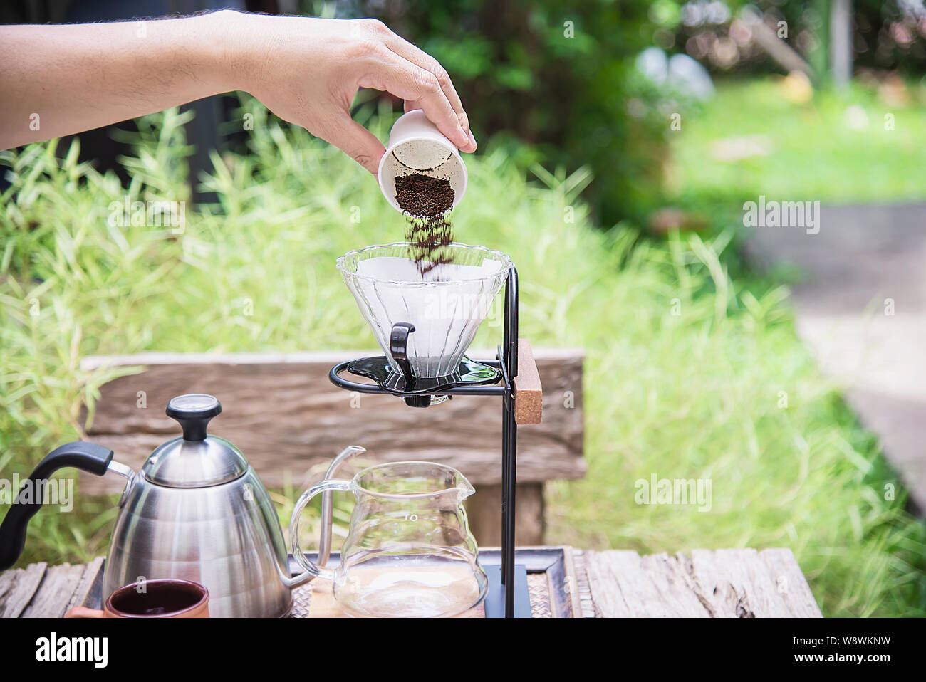 Man making drip fresh coffee in vintage coffee shop with green nature background - people with fresh coffee in nature concept Stock Photo