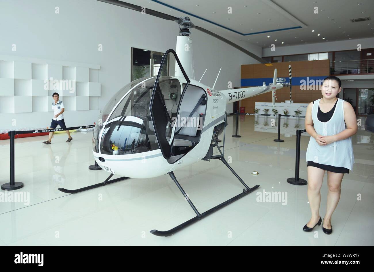 A Local Resident Walks Past An R22 Beta O Helicopter Manufactured By Robinson Helicopter Co At A Car Dealership In Hangzhou City East Chinas Zhejian Stock Photo Alamy