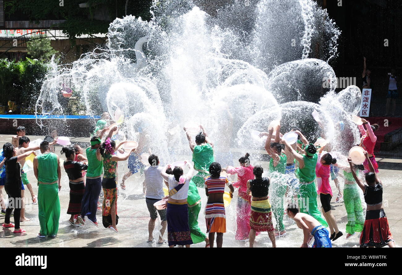 Chinese tourists and entertainers splash water during the water