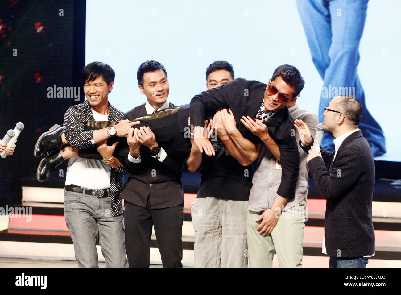 Hong Kong actors Gordon Lam Ka-tung, second left, and Sean Lau Ching-wan, center, hold up actor Louis Koo Tin-lok, front, during a press conference fo Stock Photo