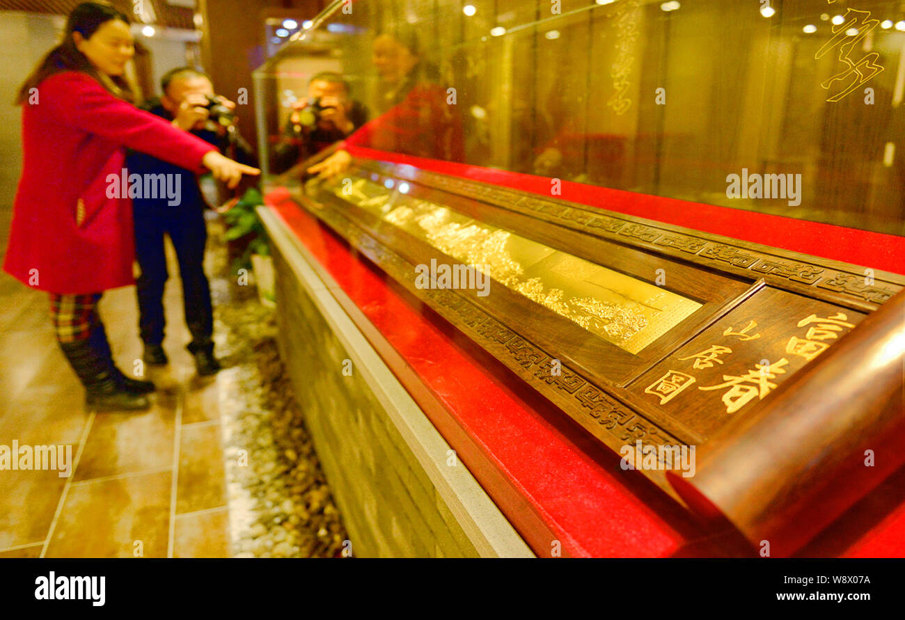 Visitors look at the gold replica of the ancient Chinese painting, Dwelling in the Fuchun Mountains, in the showroom of a gold company in Tonglu count Stock Photo