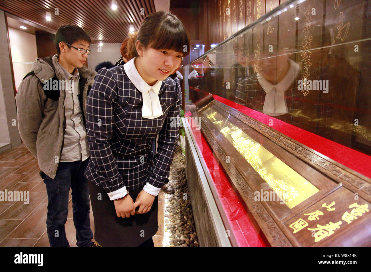 Visitors look at the gold replica of the ancient Chinese painting, Dwelling in the Fuchun Mountains, in the showroom of a gold company in Tonglu count Stock Photo