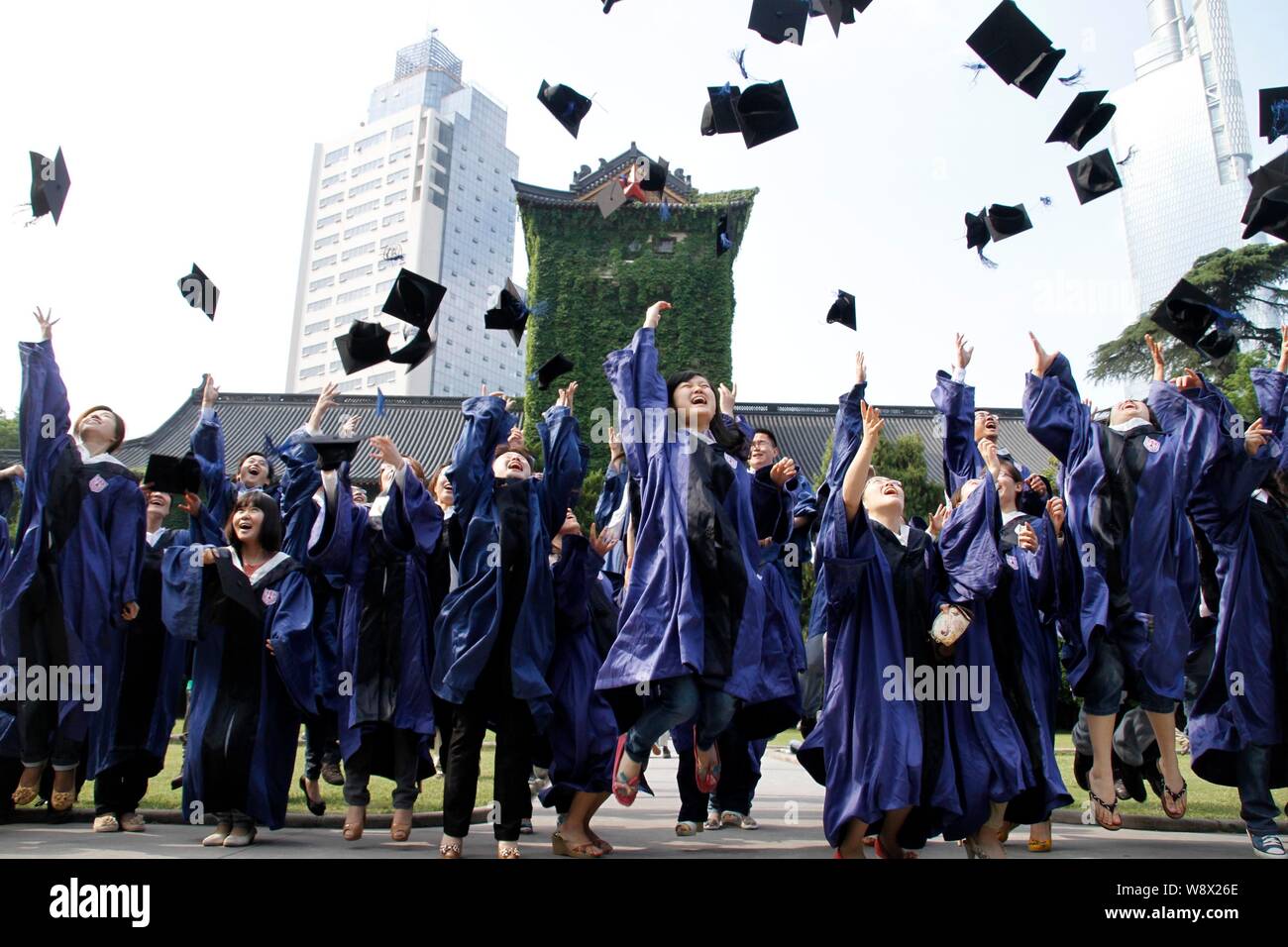 --FILE--Chinese graduates dressed in academic gowns throw their hats into the air during a graduation ceremony at Nanjing Unviersity in Nanjing city, Stock Photo