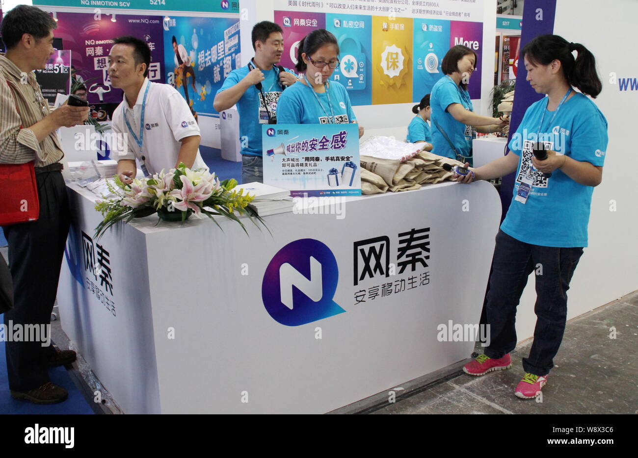 --FILE--Chinese employees are seen at the stand of NQ Mobile Inc., a Chinese mobile security services provider, during the PT/EXPO COMM China 2013 in Stock Photo