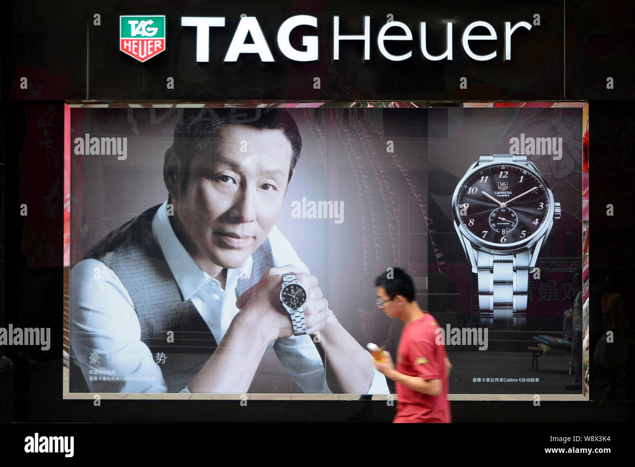 --FILE--A pedestrian walks past an advertisement for Tag Heuer watches endorsed by Chinese actor Chen Daoming in Dalian city, northeast Chinas Liaonin Stock Photo