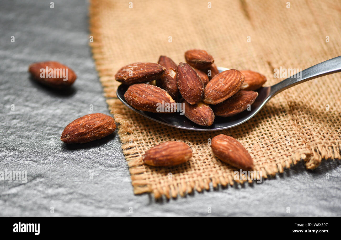 Almonds roasted in a spoon on sack , close up almonds nuts baked salt