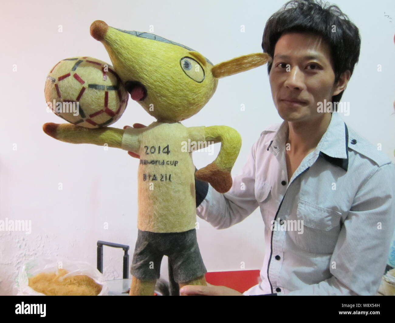 Chinese hairstylist Huang Xin poses with his hair-made Fuleco, the mascot of the 2014 FIFA World Cup Brazil, in Beijing, China, 8 May 2014.   A Chines Stock Photo