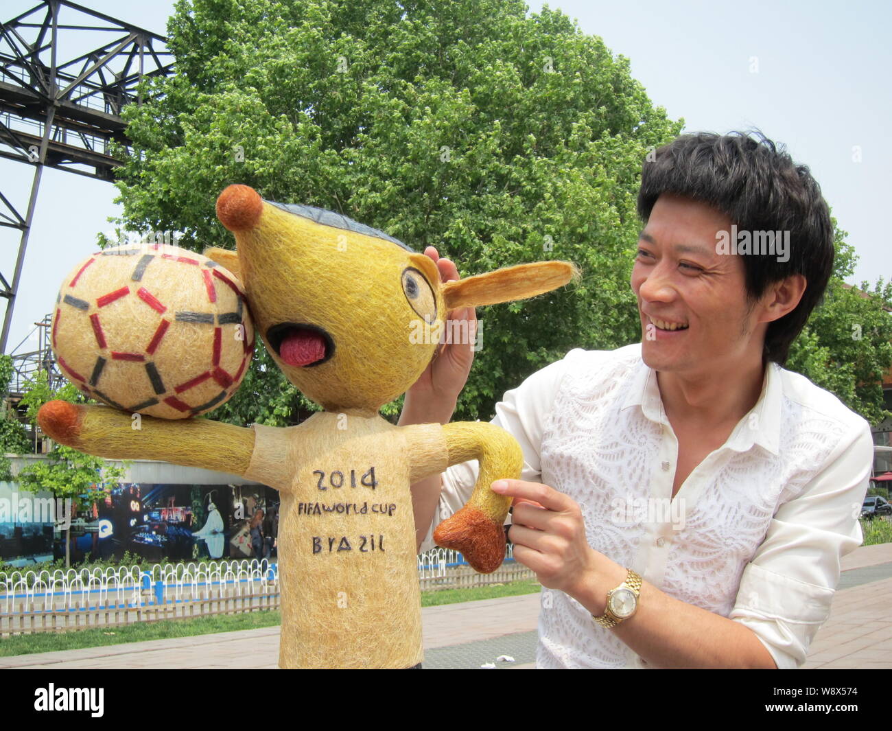 Chinese hairstylist Huang Xin poses with his hair-made Fuleco, the mascot of the 2014 FIFA World Cup Brazil, in Beijing, China, 8 May 2014.   A Chines Stock Photo