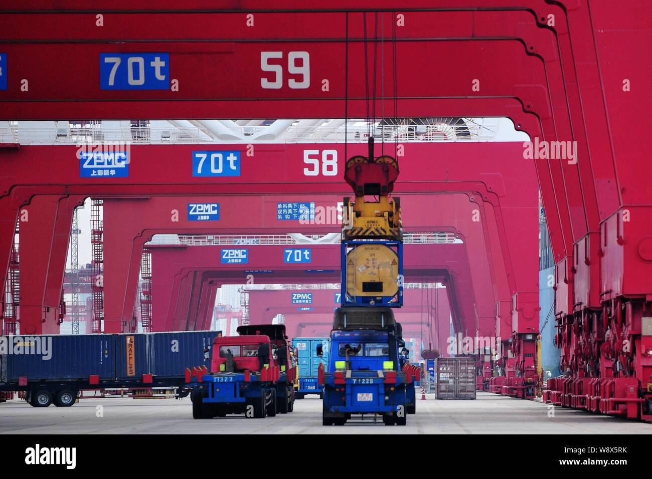 --FILE--A crane vehicle unloads a container to be exported to foreign countries from a truck at the Port of Qingdao, in Qingdao, east China's Shandong Stock Photo