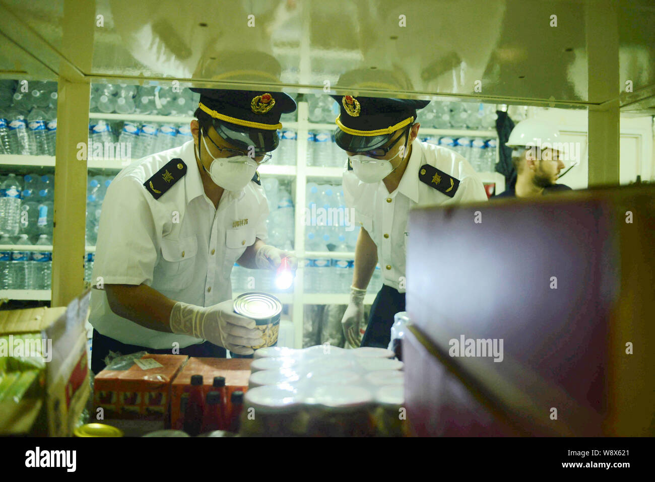 Chinese quarantine officers wearing masks examine a food cabin in the