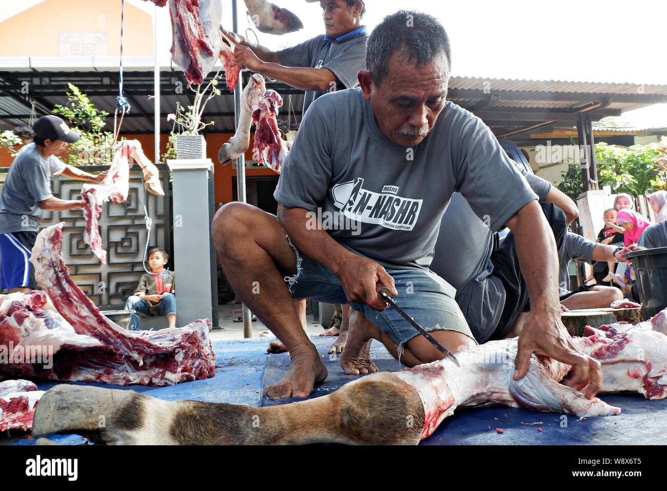 Some volunteers cut the sacrificial meat in Eid al Adha day. Eid al Adha is a traditional Islamic event when some fresh meat are given to the poor. Stock Photo