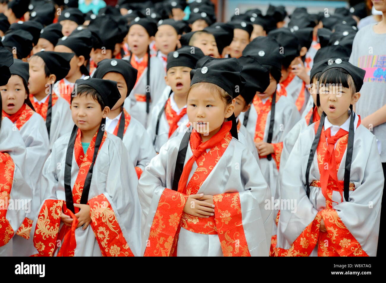 Young pupils dressed in ancient Chinese student costumes recite 'The Analects of Confucius' in front of the statue of Confucius during an unveiling ce Stock Photo