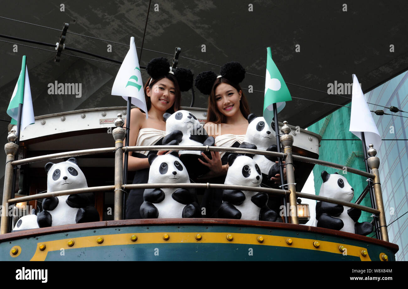 Showgirls pose with the paper pandas created by French artist Paulo Grangeon onboard a double-decker tram in a tram parade during the 1600 Pandas Worl Stock Photo