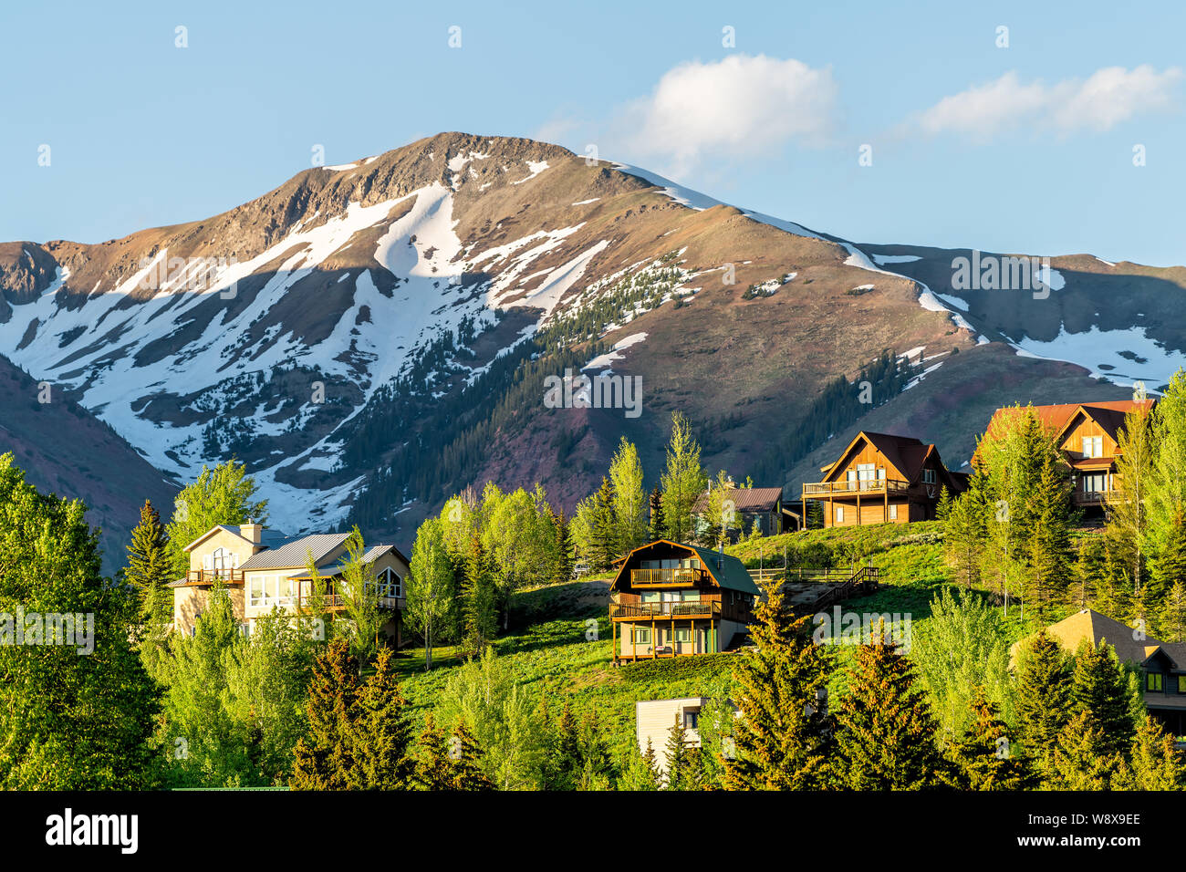 Mount Crested Butte Colorado village in summer with colorful sunset by houses on hills with green trees and main street road Stock Photo