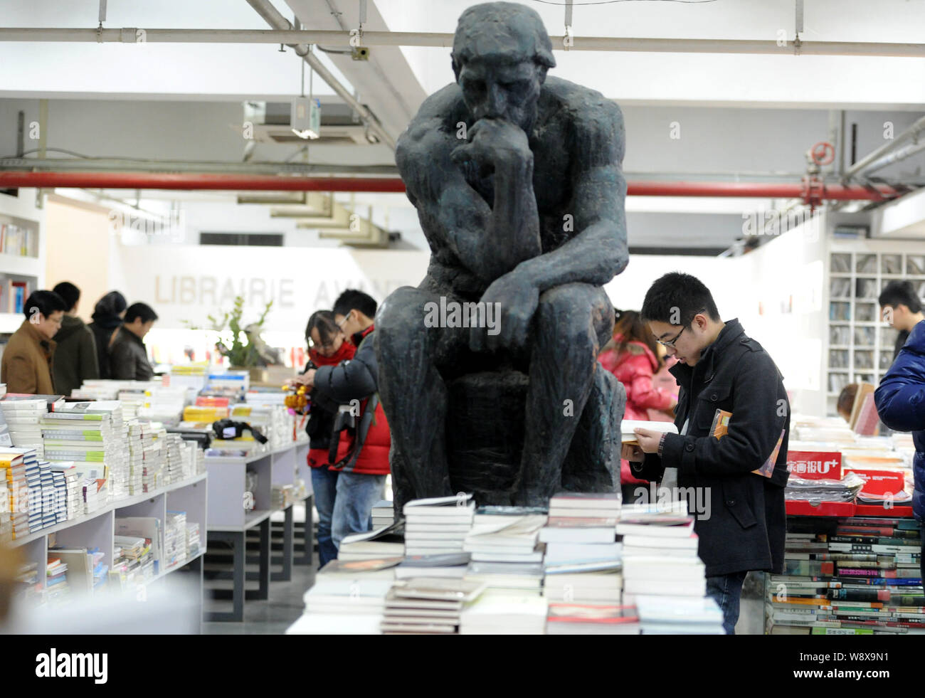 --FILE--Customers read or shop for books next to a replica of The Thinker at the Librairie Avant-Garde bookstore in Nanjing city, east Chinas Jiangsu Stock Photo