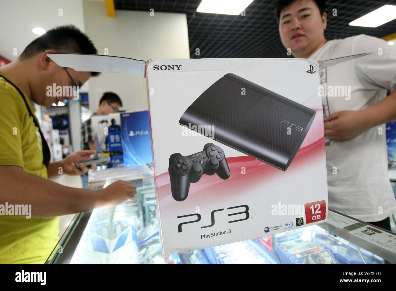 A Chinese vendor, right, serves a customer next to a smuggled Sony PlayStation 3 (PS3) game console for sale at a digital products mall in Shanghai, C Stock Photo