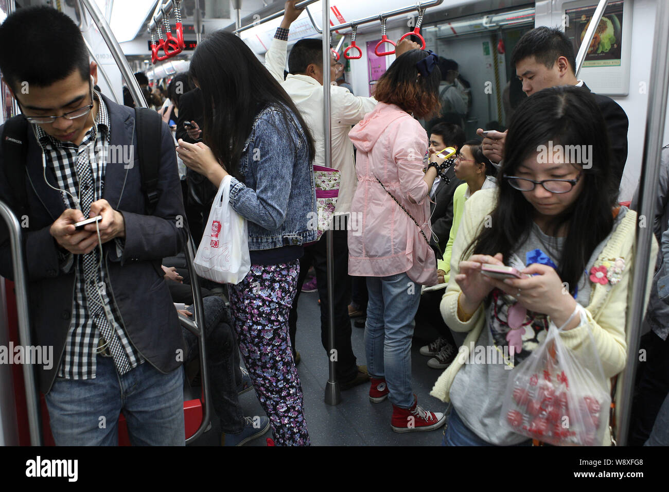 --FILE--Passengers use their smartphones to surf the Internet in a subway train in Hangzhou city, east Chinas Zhejiang province, China, 5 May 2014. Stock Photo