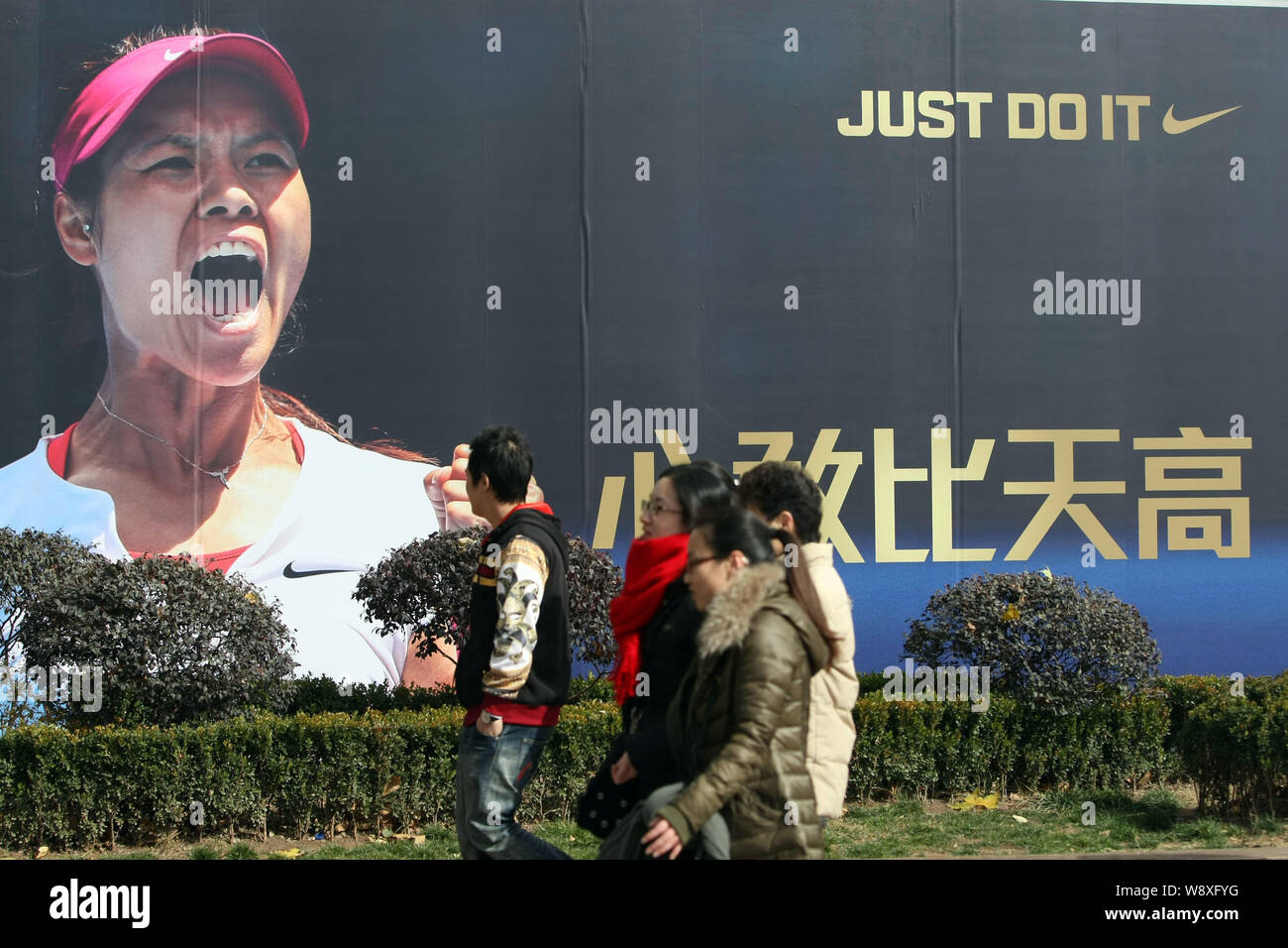 Pedestrians walk past an advertisement of Nike with the portrait of Chinese tennis star Li Na in Shanghai, China, 26 January 2014.   Li Na is confiden Stock Photo