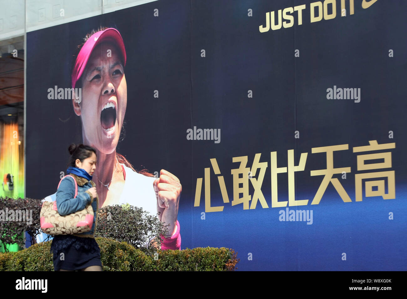 A pedestrian walks past an advertisement of Nike with the portrait of Chinese tennis star Li Na in Shanghai, China, 26 January 2014.   Li Na is confid Stock Photo