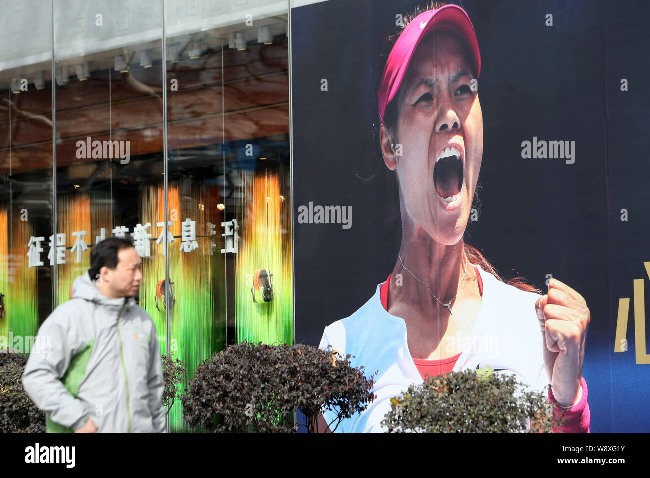 A pedestrian walks past an advertisement of Nike with the portrait of Chinese tennis star Li Na in Shanghai, China, 26 January 2014.   Li Na is confid Stock Photo