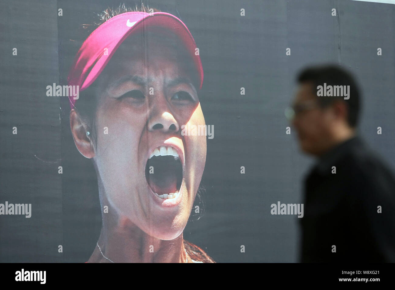 A pedestrian walks past an advertisement of Nike with the portrait of Chinese tennis star Li Na in Shanghai, China, 26 January 2014.   Li Na is confid Stock Photo