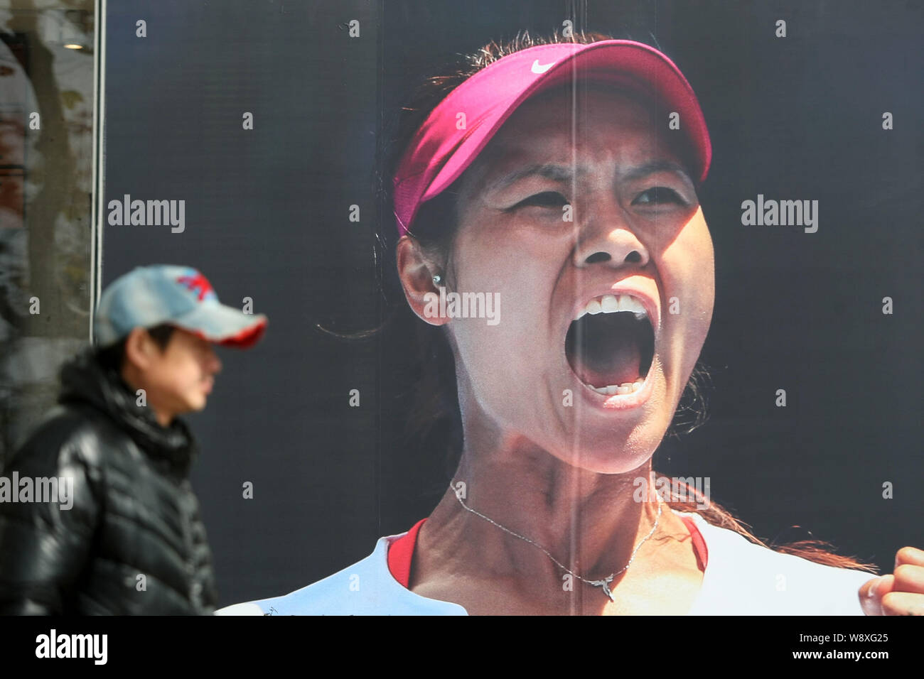 A pedestrian walks past an advertisement of Nike with the portrait of Chinese tennis star Li Na in Shanghai, China, 26 January 2014.   Li Na is confid Stock Photo