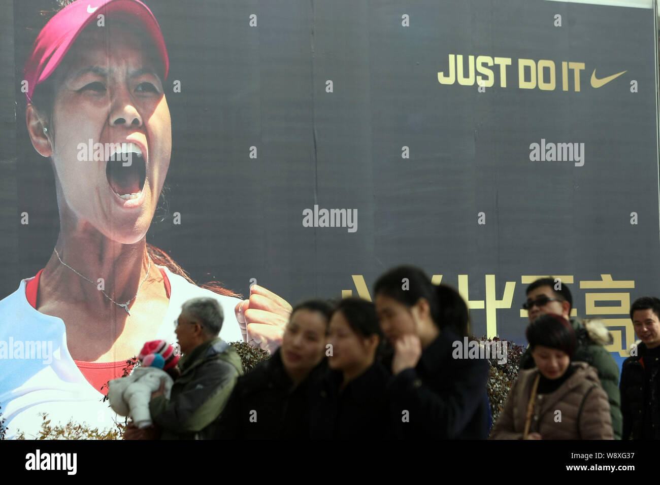 Pedestrians walk past an advertisement of Nike with the portrait of Chinese tennis star Li Na in Shanghai, China, 26 January 2014.   Li Na is confiden Stock Photo