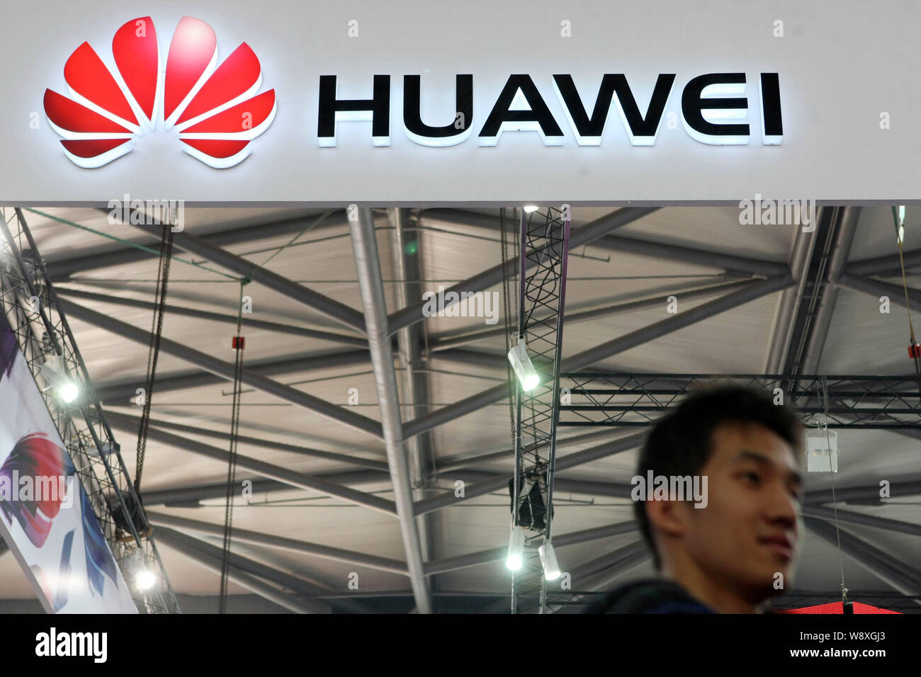 A visitor walks past the stand of Huawei at an exhibition in Shanghai, China, 21 January 2014.   Facing new efforts by a hostile Obama administration Stock Photo
