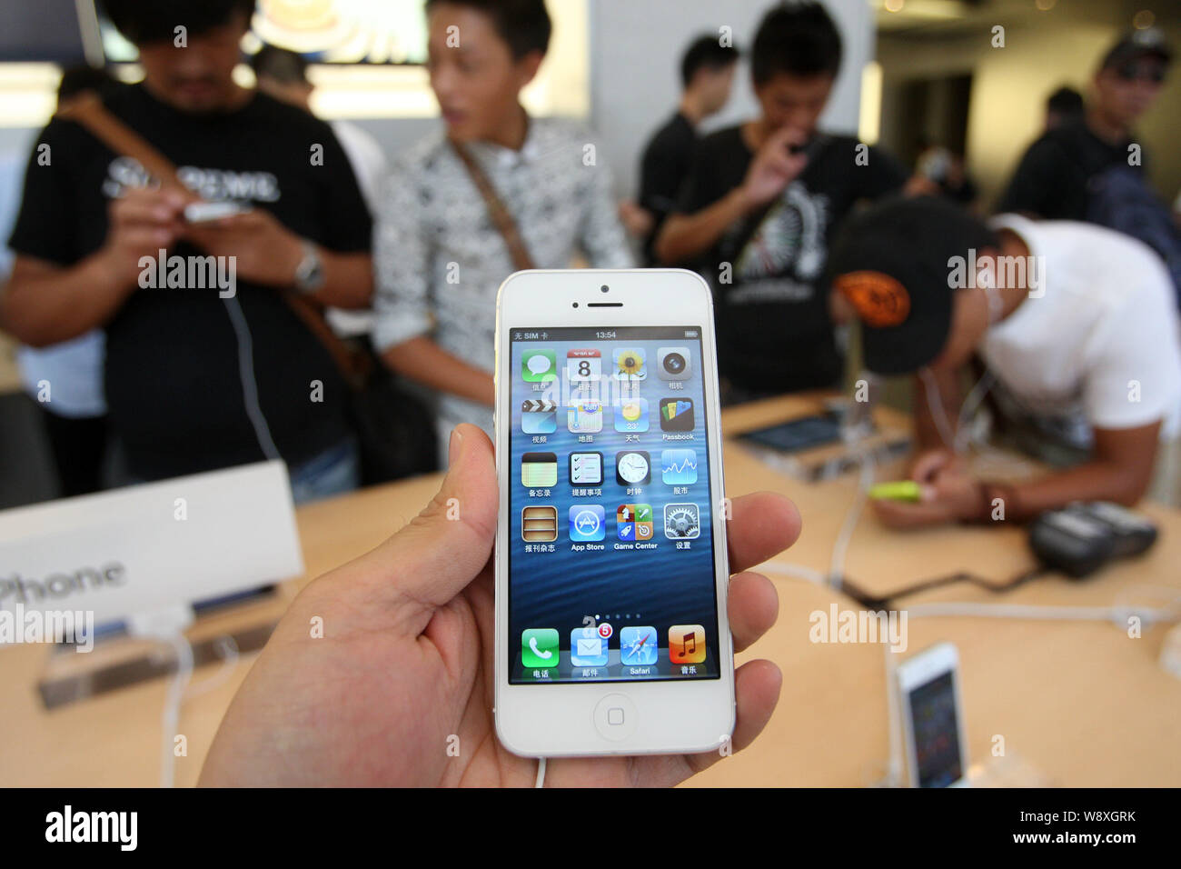 --FILE--A customer tries out an iPhone 5 smartphone at an Apple Store in Shanghai, China, 8 August 2013. Government employees should be banned from Stock Photo