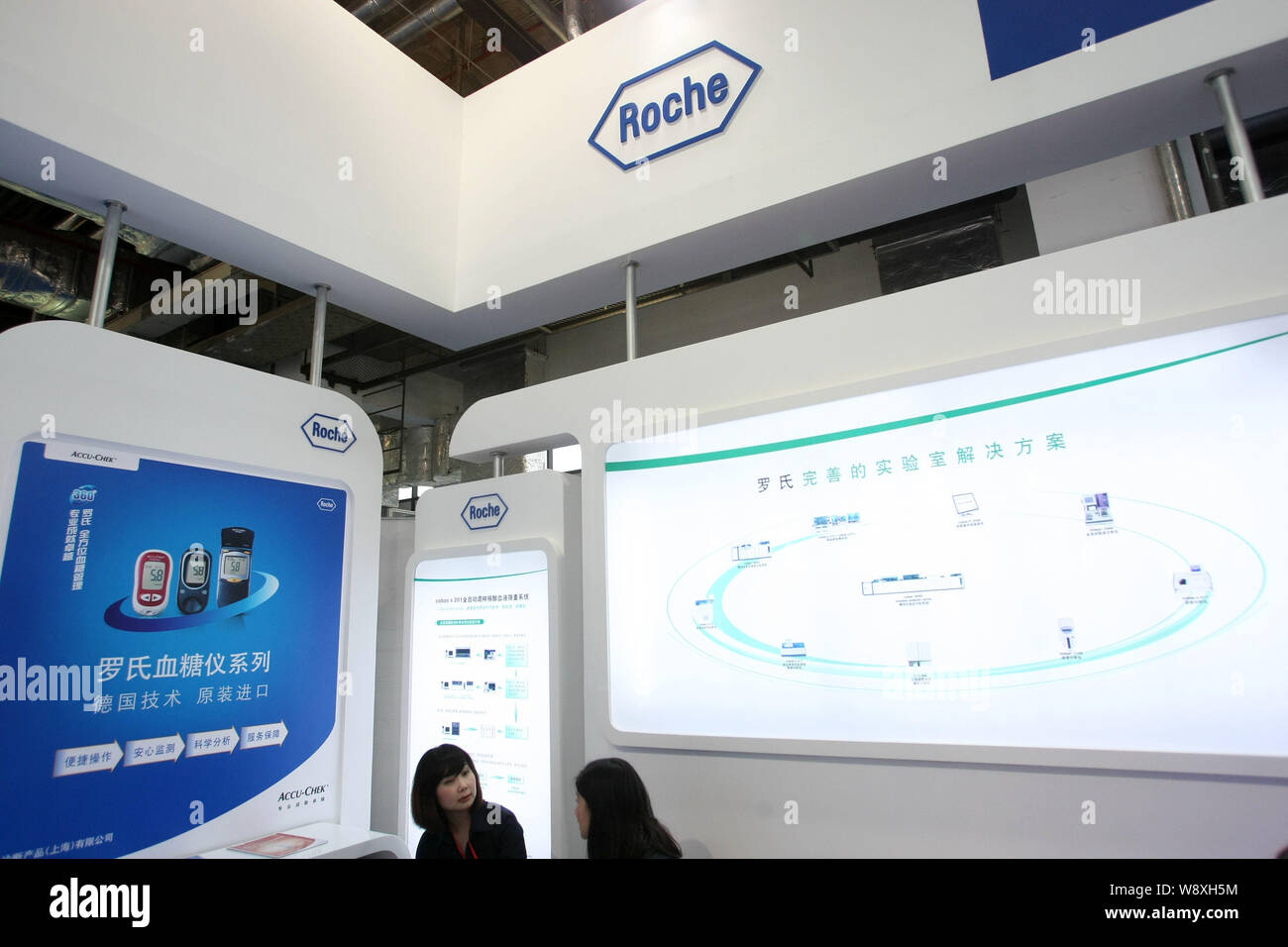 --FILE--Chinese employees are seen at the stand of Roche during the 1st China (Shanghai) International Technology Fair in Shanghai, China, 7 May 2013. Stock Photo