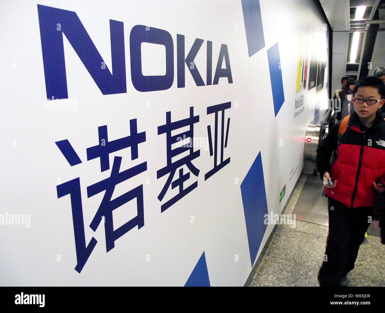 --FILE--Pedestrians walk past an advertisement for Nokia at a metro station in Nanjing city, east Chinas Jiangsu province, 30 January 2013.   Nokia Co Stock Photo