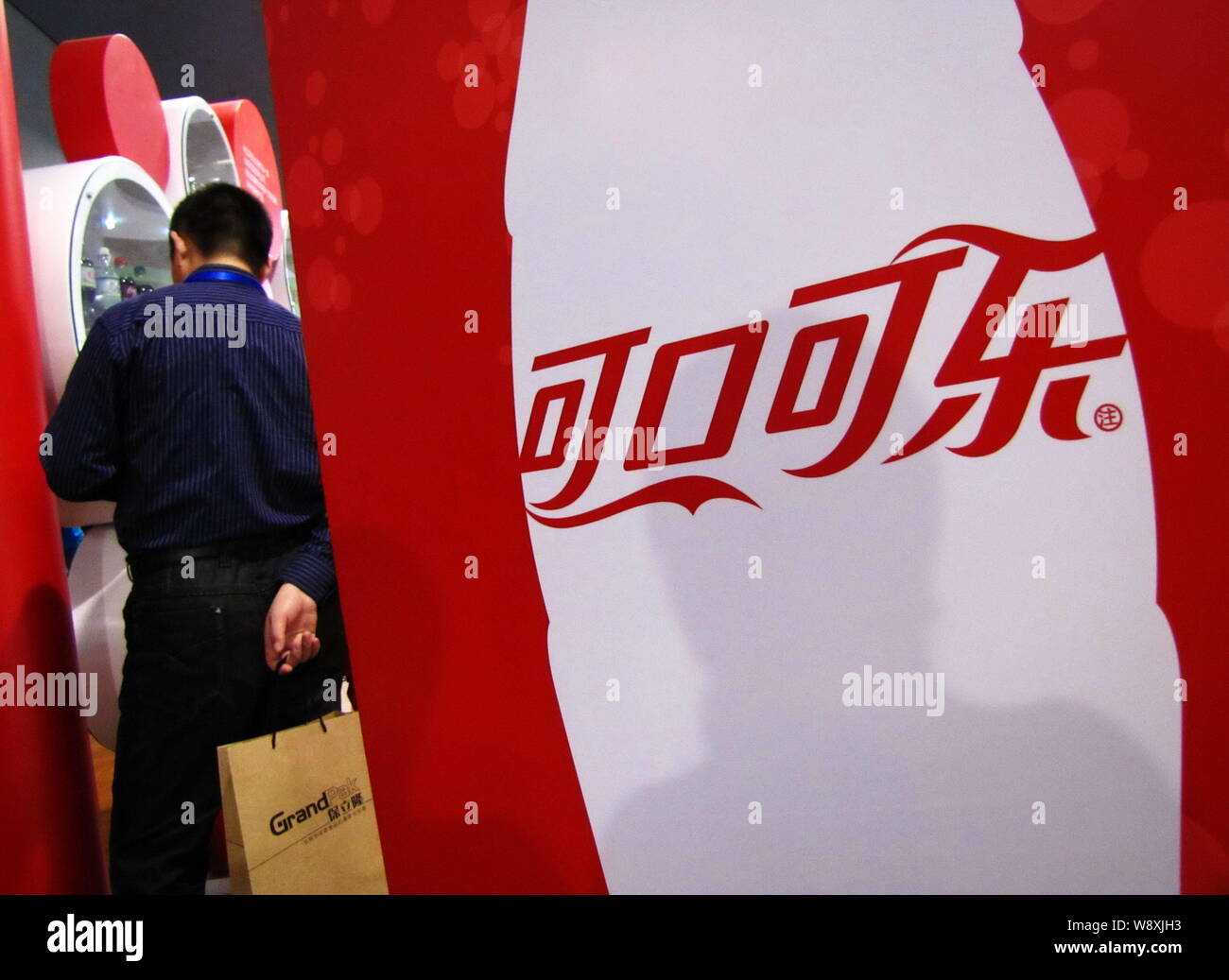 --FILE--A visitor stands next to an advertisement for Coca-Cola during ...