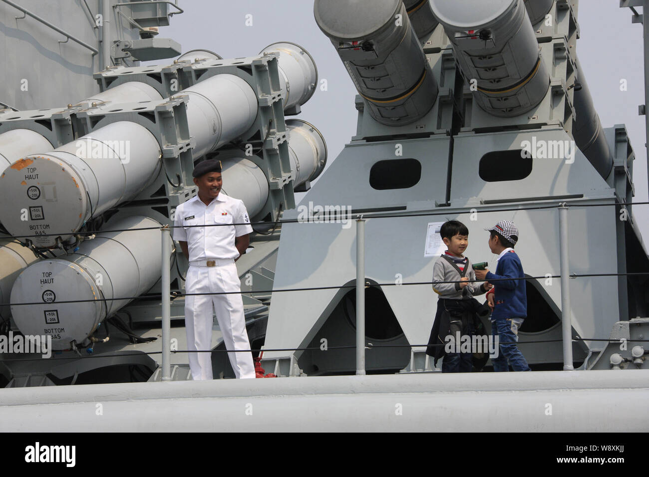 A Bruneian naval soldier, left, watches two young boys playing on the Royal Brunei naval ship KDB Darulaman at a port during the 14th Western Pacific Stock Photo