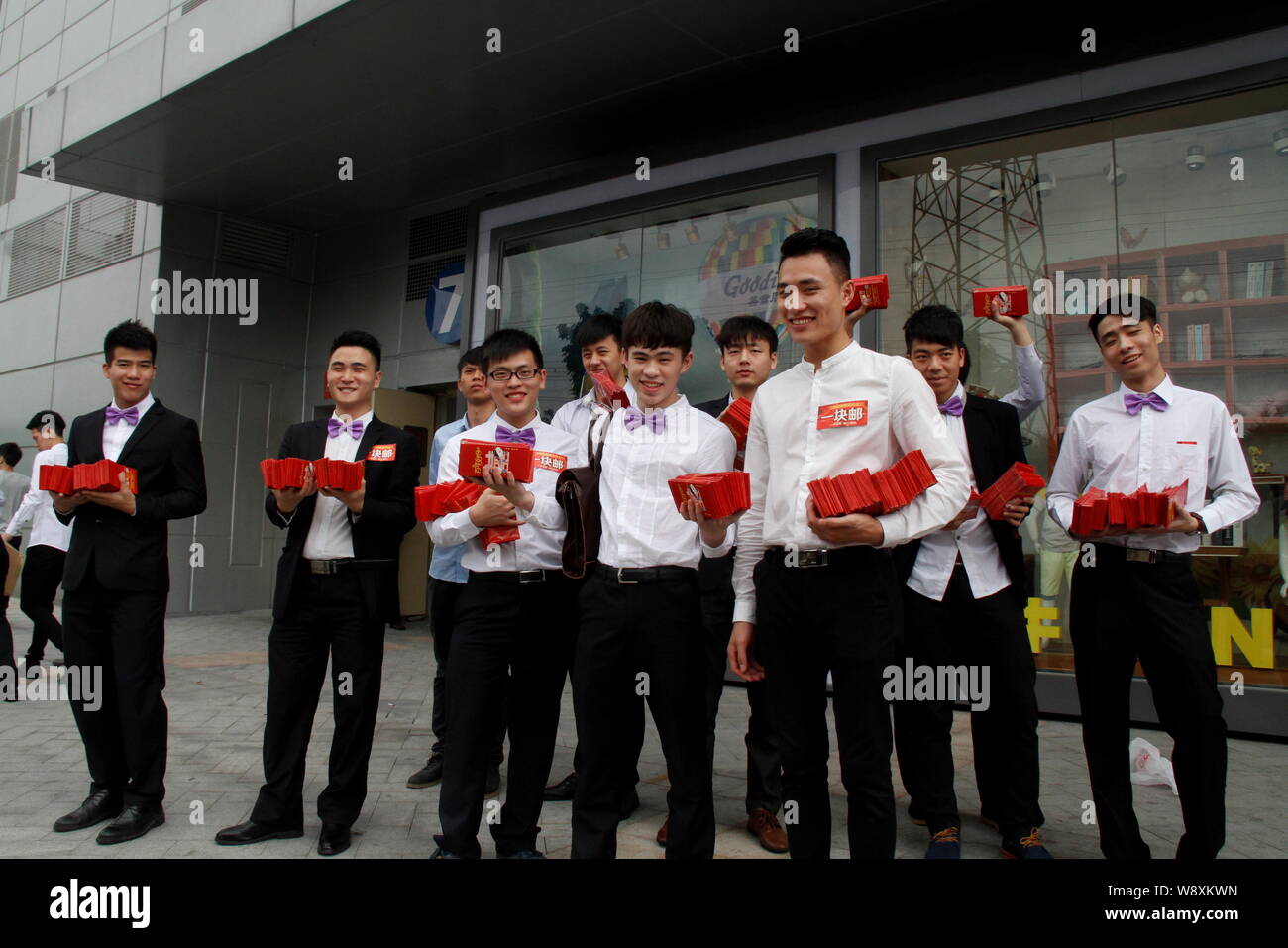 Best men of Chinese entrepreneur Chen Junliang holding Hongbao (cash-filled red envelopes) wait to give them out on a street during Chen's wedding in Stock Photo
