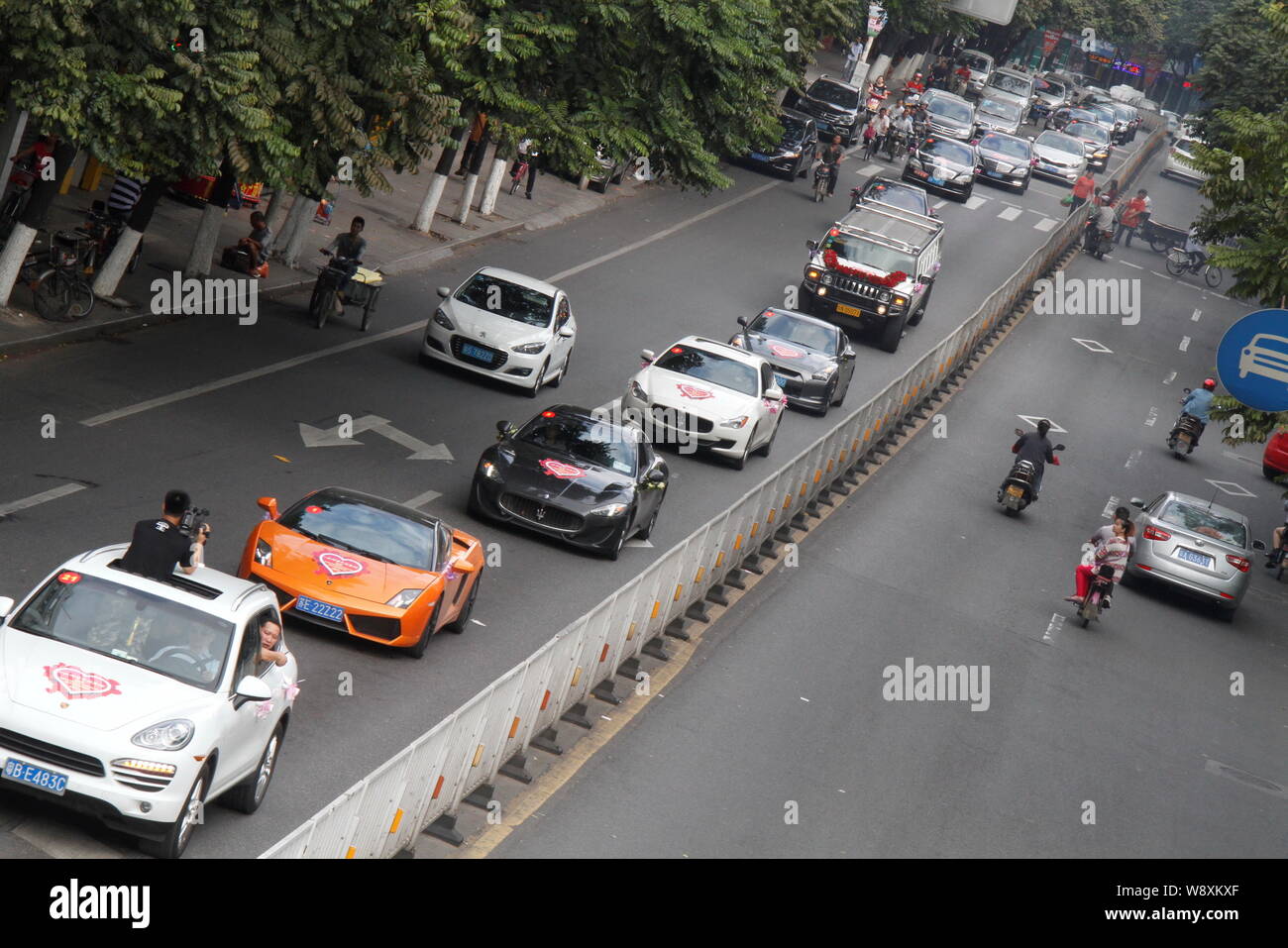 Sports cars and other vehicles in the wedding parade drive on a street during Chinese entrepreneur Chen Junliang's wedding in Dongguan city, south Chi Stock Photo
